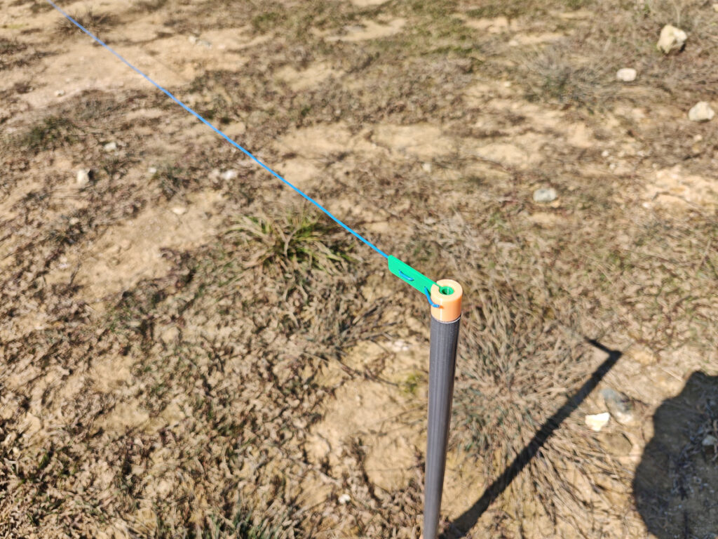 Radial wire end hooked to PVC pipe cap ground stake