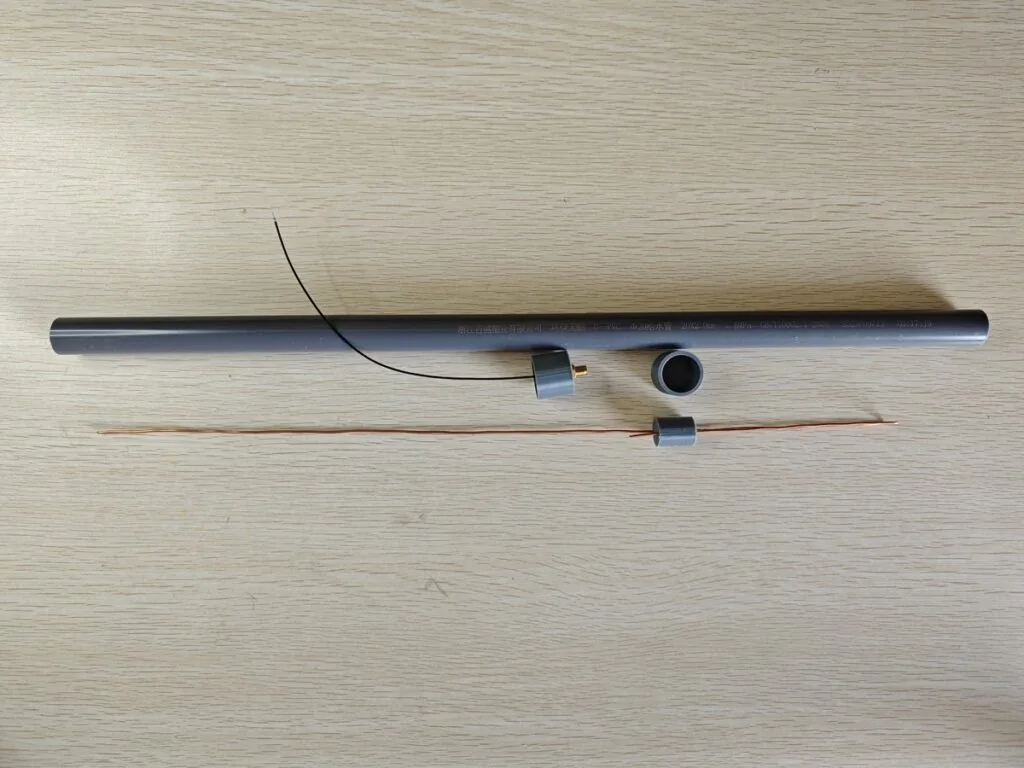 Homemade J-Pole antenna parts including PVC pipe, copper wire, spacers, and coax pigtail